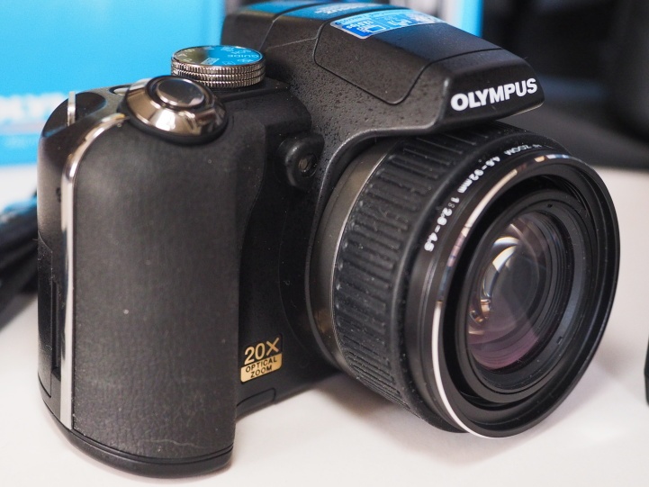 Olympus SP-565UZ s príslušenstvom .